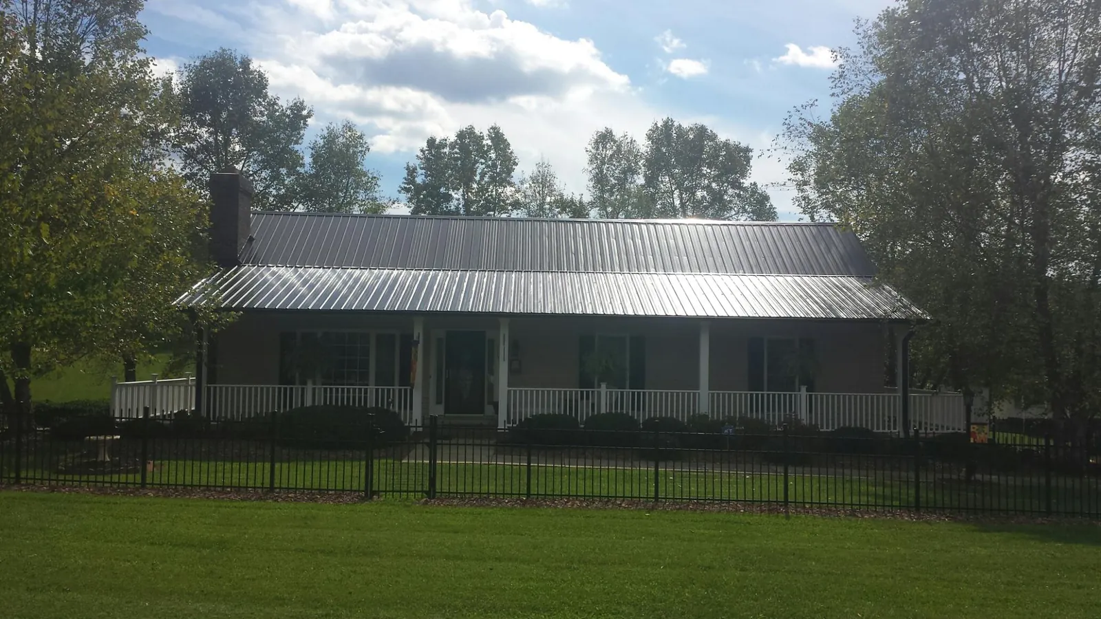 Gray metal roof on a brick ranch with a full width front porch — Gutter Guard Installation work by our crew in Montgomery